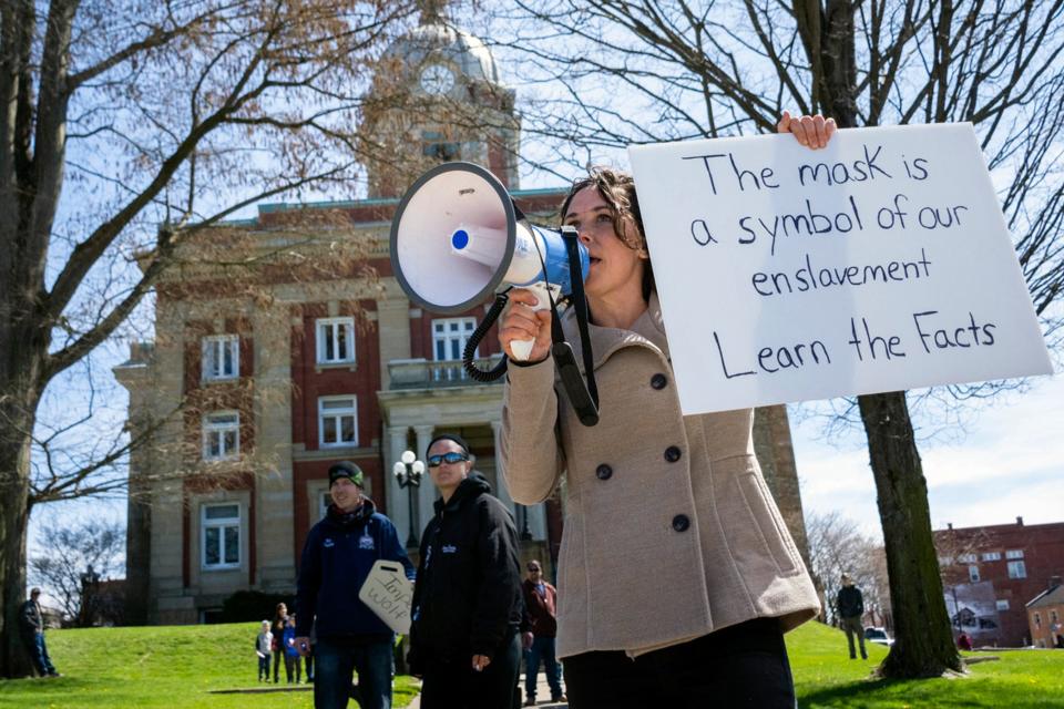 Rachel Powell, of Sandy Lake, Pa., uses a bullhorn to talk to passing cars while protesting stay-at-home orders and the shutdown of non-essential businesses due to the coronavirus pandemic outside the Mercer County Courthouse, on April 20, 2020, in Mercer, Pa.