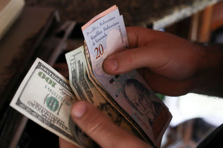 A cashier counts U.S. dollar and Venezuelan bolivar notes received from a customer in a bakery during an ongoing blackout in Caracas, Venezuela March 10, 2019. REUTERS/Manaure Quintero