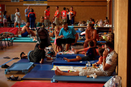 Tourists, who were evacuated due to a forest fire, rest on mats and eat a meal in a gymnasium in Bormes-les-Mimosas, in the Var department, France, July 26, 2017. REUTERS/Jean-Paul Pelissier