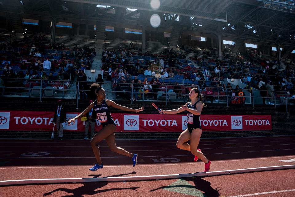 two runners exchange a baton in a race on a track