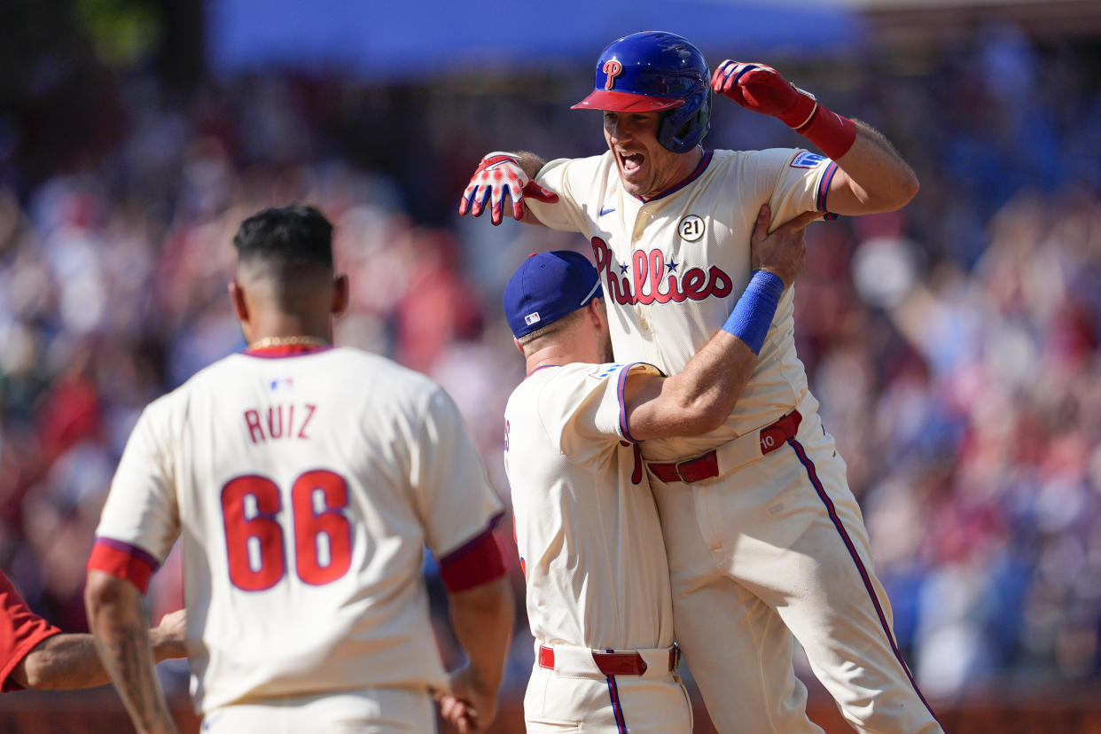 Philadelphia Phillies' J.T. Realmuto, right, jumps into the arms of Kody Clemens, center, after hitting a walkoff single off New York Mets' Edwin Díaz during the ninth inning of a baseball game, Sunday, Sept. 15, 2024, in Philadelphia. (AP Photo/Derik Hamilton)