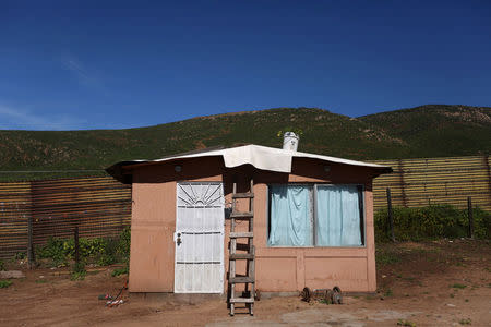 A house stands near a section of the fence separating Mexico and the United States, on the outskirts of Tijuana, Mexico. REUTERS/Edgard Garrido