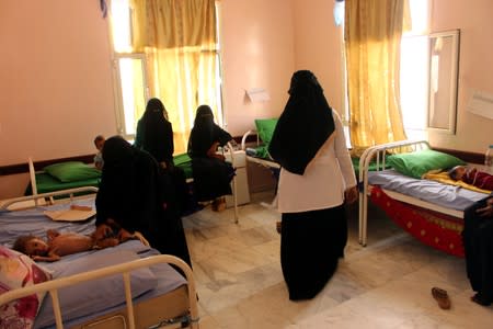 Grandmother of malnourished Muath Ali muhammad helps him as he lies on a bed at a health center in Aslam district of the northwestern province of Hajja