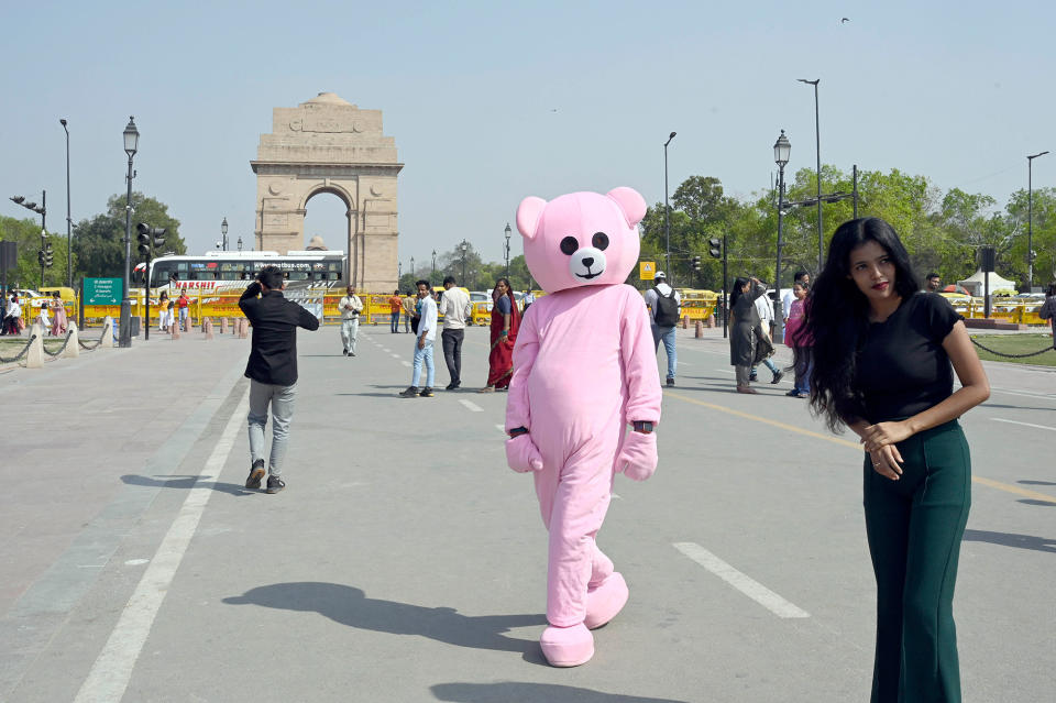 Someone in a pink bear costume walking down a street in New Delhi