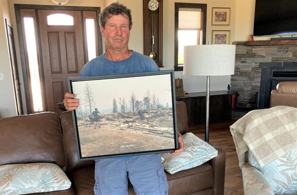 Rob MacRae holds a photo of his house after it burned down in the 2018 Carr Fire. MacRae and his wife, Leslie, have since rebuilt their home in Keswick.