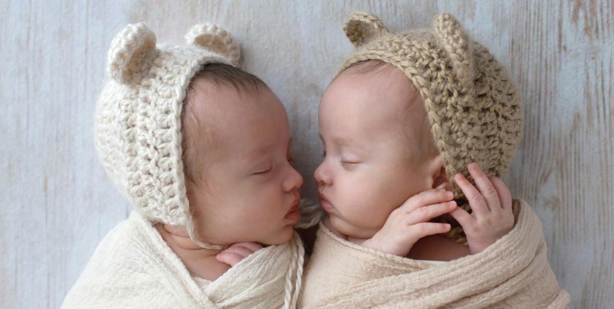 baby girls sleeping they are wearing crocheted bear hats and are swaddled in cream and tan wraps