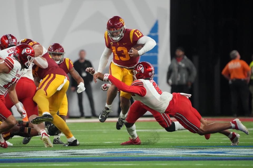 Southern California quarterback Caleb Williams (13) tries to avoid the tackle effort of Utah safety Cole Bishop (8) during the first half of the 2022 Pac-12 championship game at Allegiant Stadium in Las Vegas.