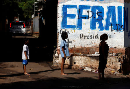 People stand in front of a wall painted with the name of Presidential candidate of the GANAR coalition Efrain Alegre ahead of the April 22 elections, in Asuncion, Paraguay April 20, 2018. REUTERS/Andres Stapff