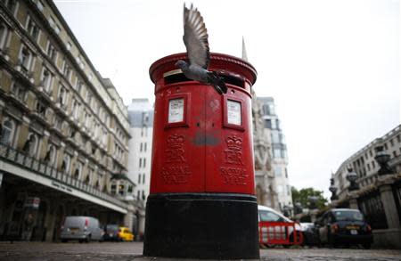 A pigeon flies past a Royal Mail post box outside Charing Cross station in central London, October 8, 2013. REUTERS/Andrew Winning