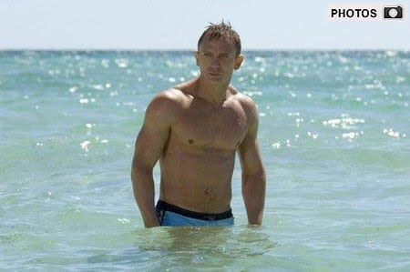 daniel craig, blue swim trunks, 007, beach scene.