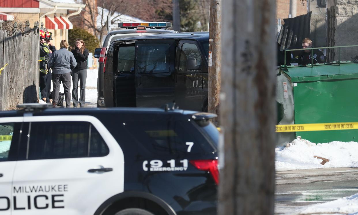 Police investigate three bodies found in a garage in the 4700 block of West Burleigh Street in Milwaukee. Here they work in an alley near dumpsters behind a building.