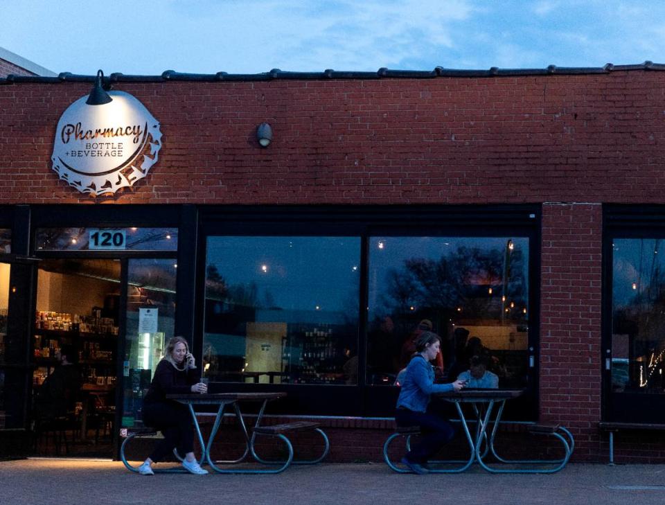 People sit outside at Pharmacy Bottle + Beverage on Thursday, March 16, 2023, in Cary, N.C.