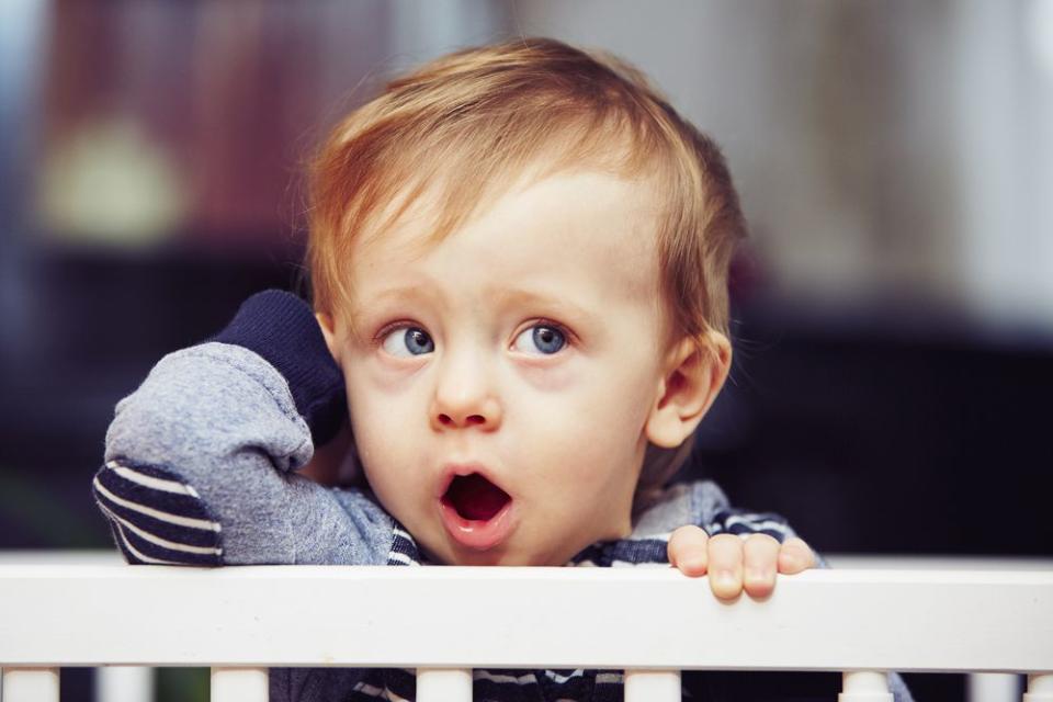 yawning toddler boy in crib