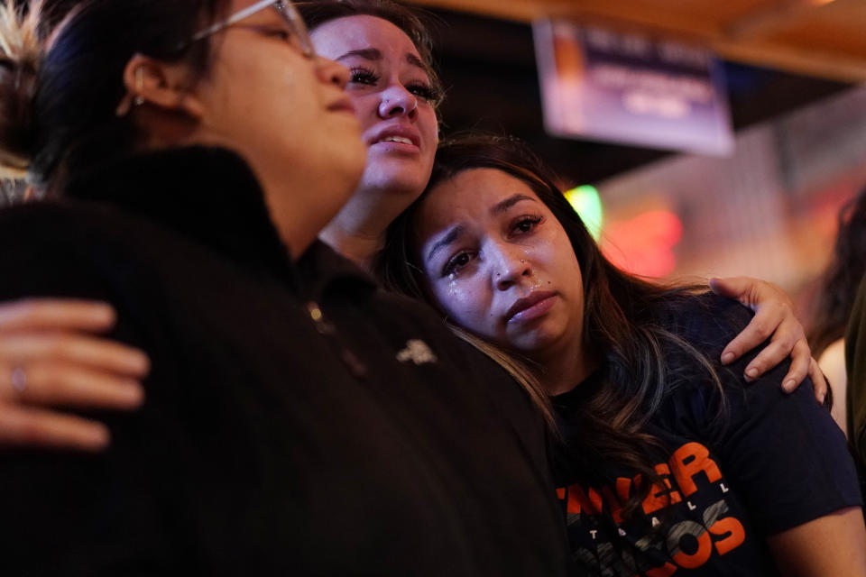 Bryanna Saiz, right, cries with others during a memorial for Jackson Zinn at a Texas Roadhouse restaurant, Thursday, March 17, 2022, in Hobbs, New Mexico. Zinn, who worked at the restaurant, was killed with several other student golfers and the coach of University of the Southwest in a crash in Texas. (AP Photo/John Locher)