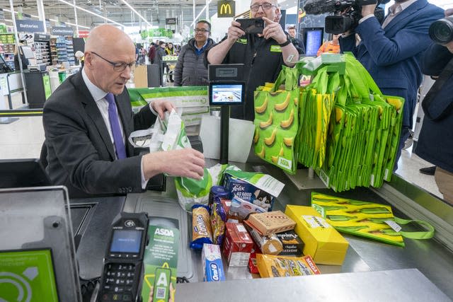 Scottish First Minister John Swinney helping out on the checkout at Asda Chesser Supermarket, in Edinburgh