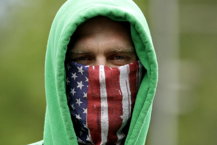 FILE - In this May 4, 2020, file photo, a man wears a mask as he waits in line outside the Warrensburg License Office in Warrensburg, Mo. (AP Photo/Charlie Riedel, File)