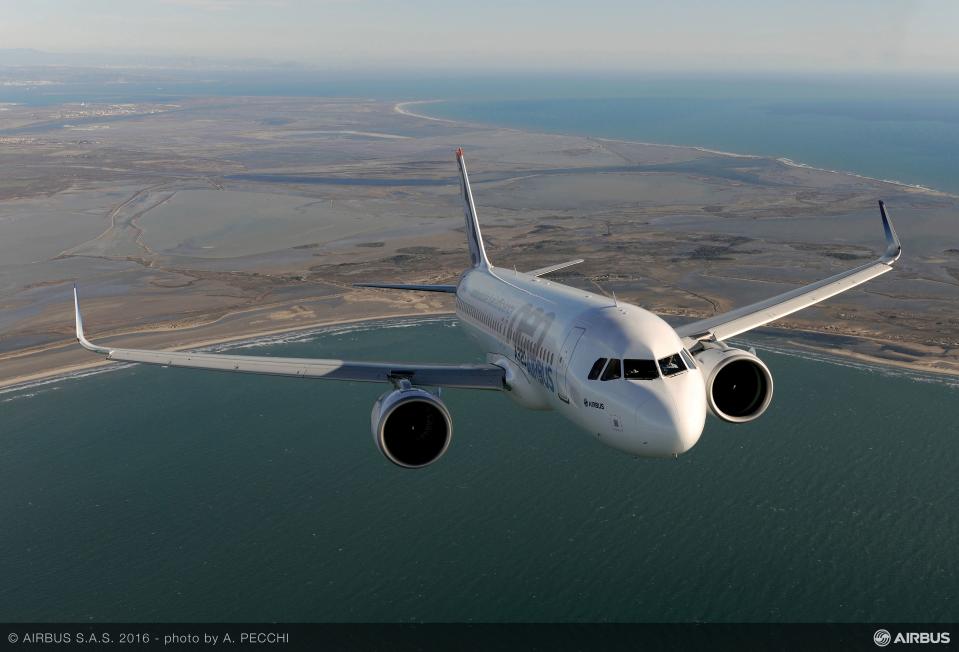 A head-on view of an Airbus A320neo flying over water.