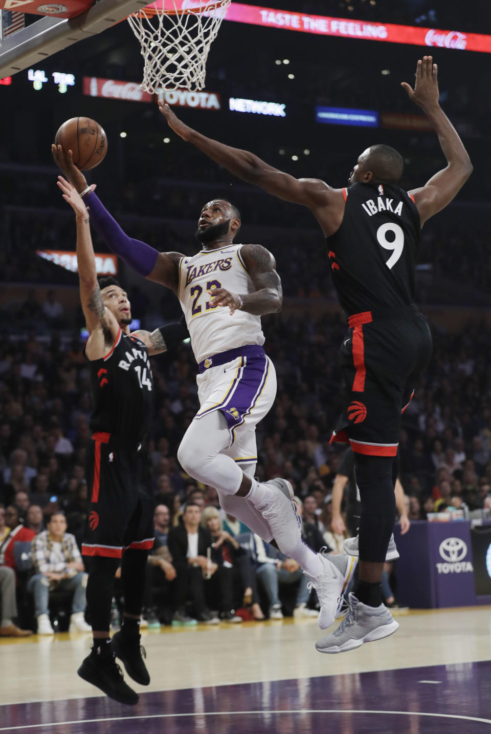 Los Angeles Lakers' LeBron James (23) drives to the basket between Toronto Raptors' Serge Ibaka (9) and Danny Green (14) during the first half of an NBA basketball game Sunday, Nov. 4, 2018, in Los Angeles. (AP Photo/Marcio Jose Sanchez)