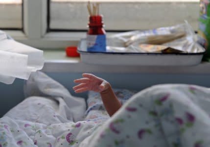 A baby stretches its hand from under a quilt at a local hospital in Jiaxing, Zhejiang province October 25, 2011. REUTERS/Stringer