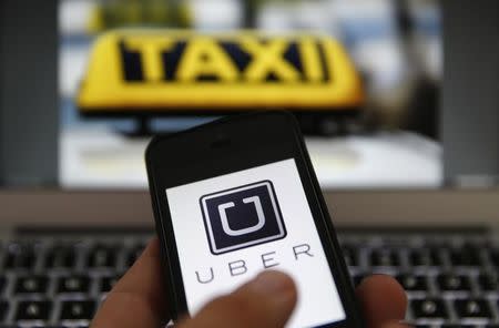 An illustration picture shows the logo of car-sharing service app Uber on a smartphone next to the picture of an official German taxi sign in Frankfurt, September 15, 2014. REUTERS/Kai Pfaffenbach/File Photo