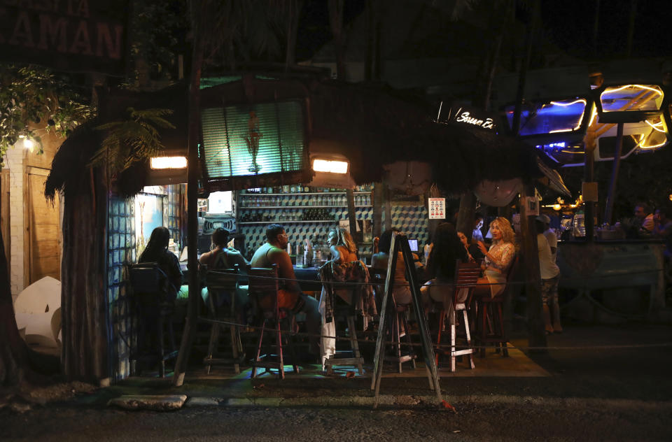 Tourists chat at a local bar on the main tourist strip of Tulum, Quintana Roo state, Mexico, Monday, Jan. 4, 2021. More U.S. tourists came to Quintana Roo during this pandemic-stricken holiday season than did a year earlier when the world was just beginning to learn of the coronavirus. They account for 9 out of 10 foreign tourists, said state Tourism Secretary Marisol Vanegas. (AP Photo/Emilio Espejel)