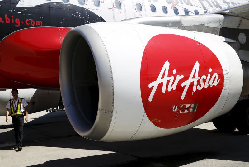 A member of ground staff walks under the wing of an Air Asia plane at Kota Kinabalu airport, Malaysia