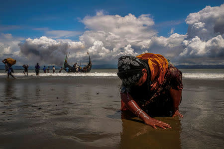 An exhausted Rohingya refugee woman touches the shore after crossing the Bangladesh-Myanmar border by boat through the Bay of Bengal, in Shah Porir Dwip, Bangladesh September 11, 2017. REUTERS/Danish Siddiqui