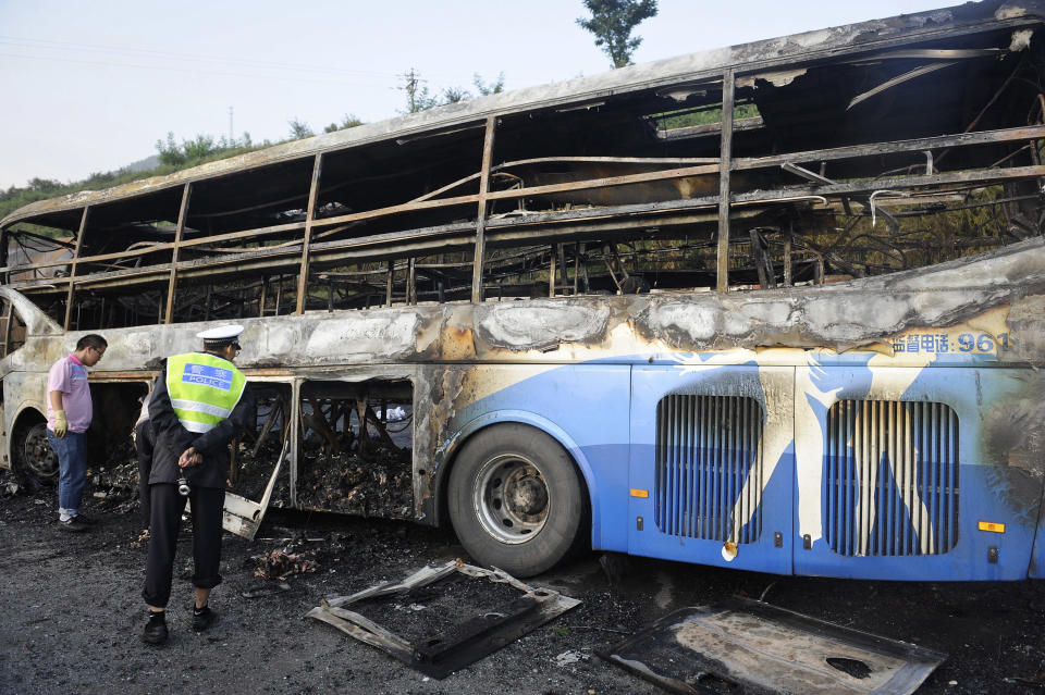 A policeman looks at a burnt-off bus after it collided with a tanker on an expressway in Yan'an in northwest China's Shaanxi province Sunday, Aug. 26, 2012. The double-decker sleeper bus rammed into the tanker loaded with highly-flammable methanol on a northern Chinese highway on Sunday, causing both vehicles to burst into flames and killing 36 people, state media said. (AP Photo) CHINA OUT
