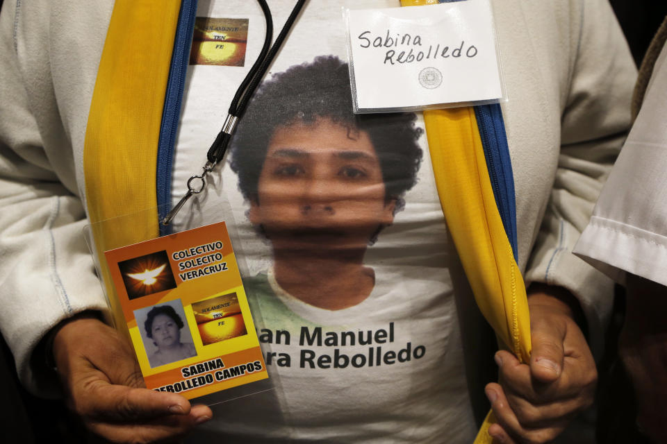 A woman with the volunteer group "Colectivo Solecito," or Little Sun Collective, holds photos of her missing relative during an award ceremony in Mexico City, Tuesday, Oct. 16, 2018. The University of Notre Dame has presented its 2018 Notre Dame Award to the group of Mexican mothers who have led a tireless, years-long search for missing loved ones in the Gulf coast state of Veracruz. (AP Photo/Marco Ugarte)