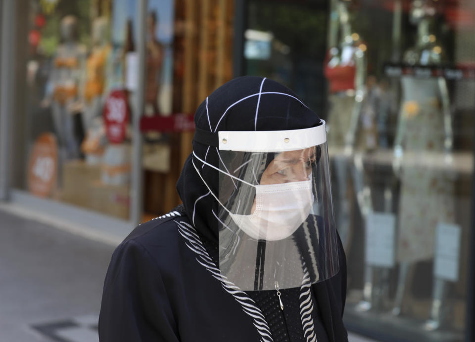 A woman wearing a face mask and a shield to protect against the spread of coronavirus, walks in the city's historical part of Ulus, in Ankara, Turkey, Thursday, June 18, 2020. Turkish authorities have made the wearing of masks mandatory in three major cities to curb the spread of COVID-19 following an uptick in confirmed cases since the reopening of many businesses.(AP Photo/Burhan Ozbilici)