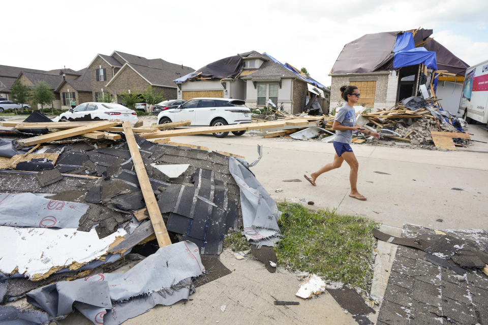 A woman walks past debris in a Bridgeland neighborhood as families begin cleaning up storm damage on Sunday, May 19, 2024, in Cypress, Texas. (Brett Coomer/Houston Chronicle via AP)