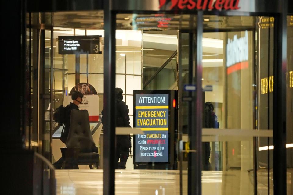 Police officers walk past a sign at Westfield Shopping Centre on Saturday (AP)