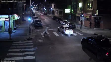 A still image from surveillance video shows a gunman (L) approaching a Philadelphia Police vehicle in which Officer Jesse Hartnett was shot shortly before midnight January 7, 2016 in Philadelphia, Pennsylvania this Philadelphia Police Department image released on January 8, 2016. REUTERS/Philadelphia Police Department/Handout