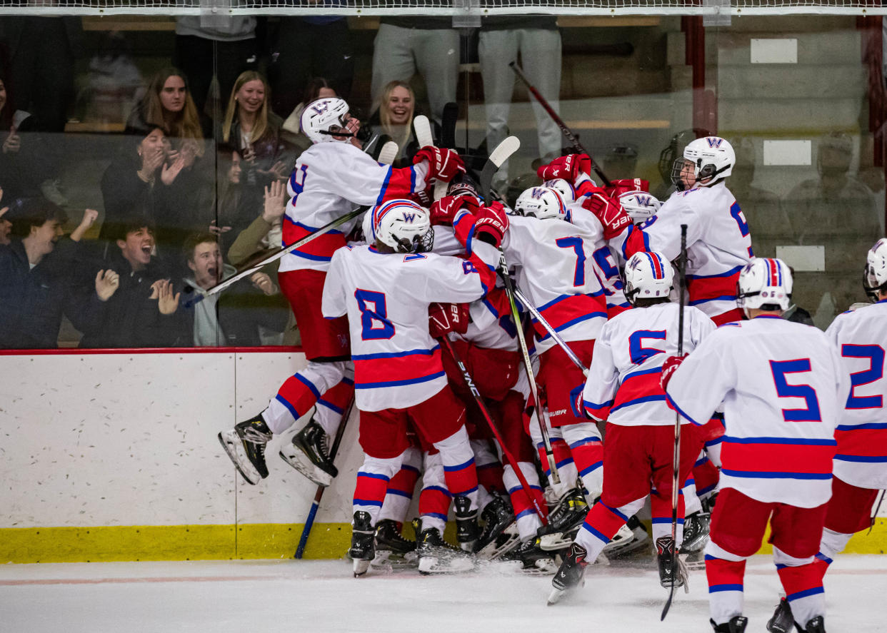 Members of the Winnacunnet High School boys hockey team celebrate after Brayden Emery's game-winning overtime goal against Spaulding on Saturday at Phillips Exeter Academy. The Warriors rallied from a 3-1 deficit and pulled out a 4-3 win.