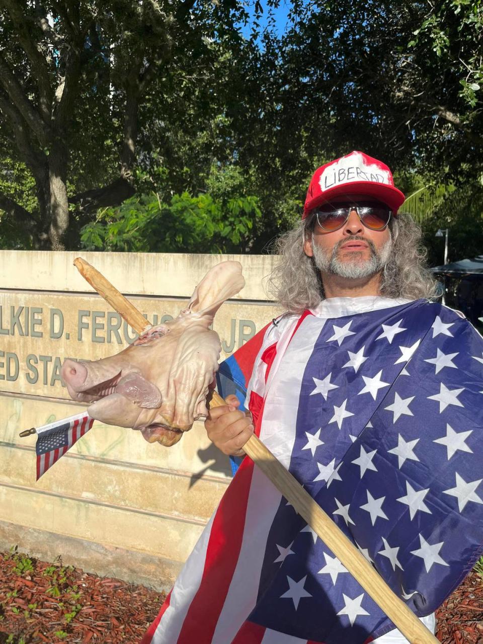 Osmani Estrada, 40, poses with a severed pig head outside the federal courthouse in Miami on Tuesday, June 13, 2023. He said he’s there to show support for the democratic process working as it should.