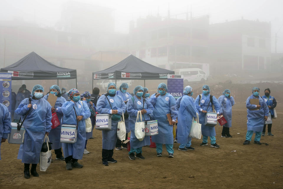 Los trabajadores de la salud sostienen hieleras con dosis de las vacunas Pfizer y Moderna para el COVID-19, así como vacunas contra la influenza, antes de ir de puerta en puerta para una campaña de vacunación en el barrio Ticlio Chico en las afueras de Lima, Perú, en el primer día oficial de invierno, el martes 21 de junio de 2022. (Foto AP/Martín Mejía)