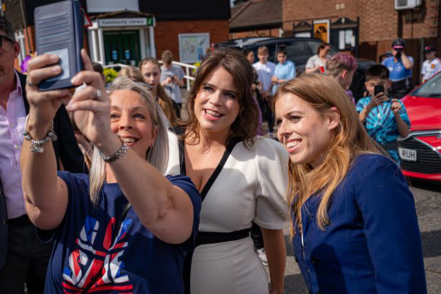 <p>Ben Birchall - WPA Pool/Getty</p> Princess Eugenie and Princess Beatrice pose for a picture with a well-wisher during a Coronation Big Lunch in Chalfont St Giles, Buckinghamshire on May 7, 2023.