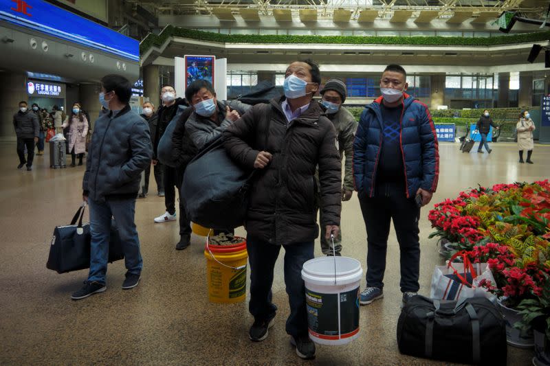 Travellers walk with their belongings at a railway station in Beijing