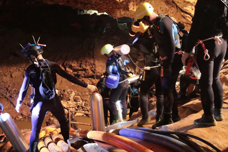 Thai rescue teams walk through the cave, carrying tanks of oxygen. Source: AP