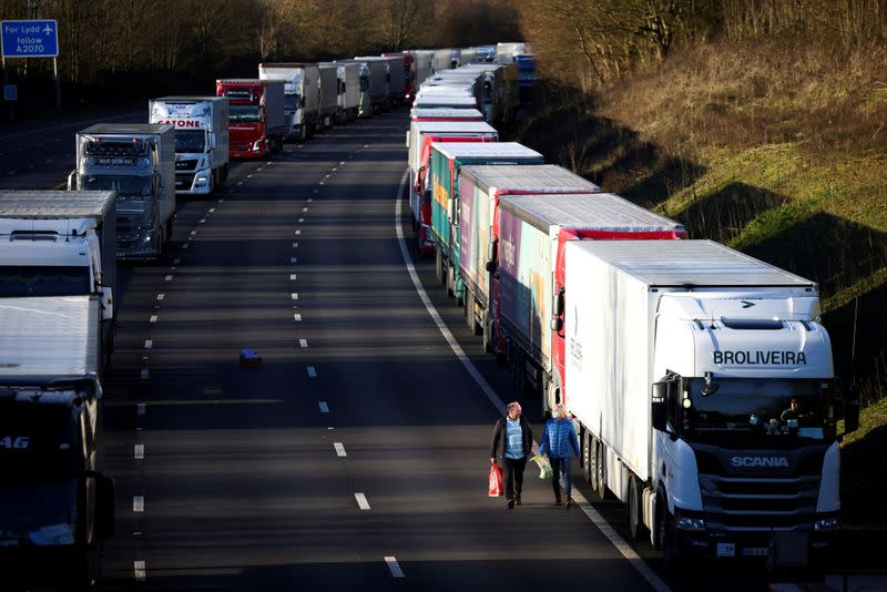 People walk by a line of parked lorries on the outskirts of Ashford