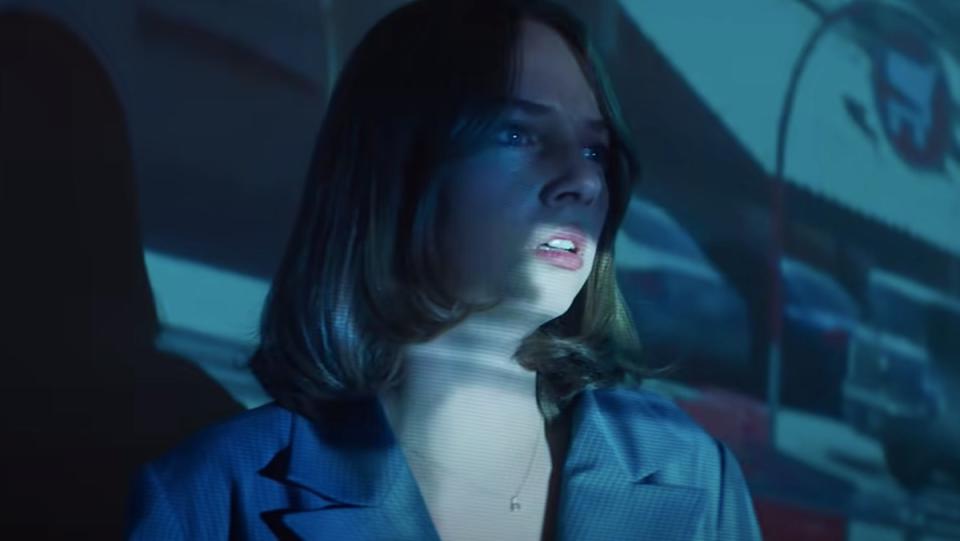 Maya Hawke's Frankie looks concerned and is drenched in blue light in a scene from Mainstream.