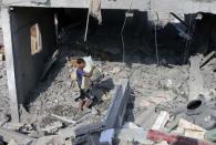 A Palestinian carries belongings from a house, which witnesses said was hit by an Israeli air strike, in Rafah, southern Gaza, in this August 2, 2014 file photo. REUTERS/Ibraheem Abu Mustafa