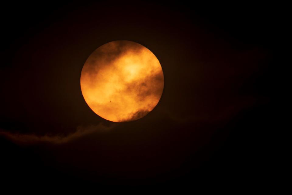 The sun briefly peaks through the clouds Saturday, Oct. 14, 2023, on the morning of the annular solar eclipse in this picture taken in Oregon.