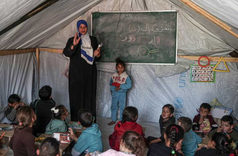 Une enseignante fait un cours à ses élèves le 27 mars 2024 dans une tente d'un camp de déplacés palestiniens à Rafah, dans le sud de la bande de Gaza, où une guerre oppose Israël au mouvement islamiste Hamas (SAID KHATIB)