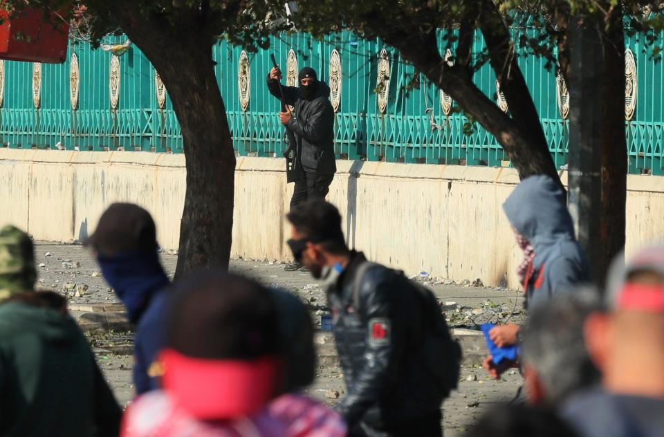 A police officer carries a pellet air rifle during clashes with anti-government protesters in Baghdad, Iraq, Friday, Jan. 31, 2020. (AP Photo/Hadi Mizban)