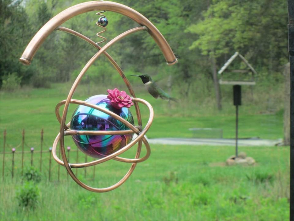 Metal, artistic bird feeder in foreground