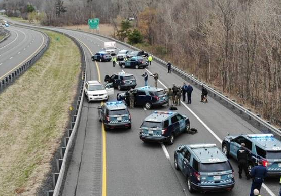 Troopers, some with guns drawn, confront the suspect on the Massachusetts Turnpike in Stockbridge.