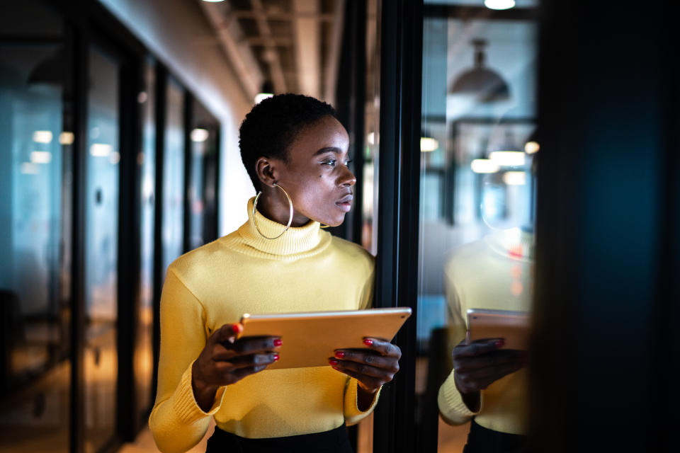 Young business woman using digital tablet and looking away in an office