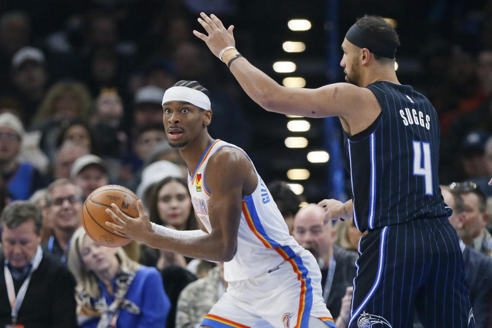 Oklahoma City Thunder guard Shai Gilgeous-Alexander, left, looks to pass the ball next to Orlando Magic guard Jalen Suggs (4) during the first half of an NBA basketball game, Saturday, Jan. 13, 2024, in Oklahoma City. (AP Photo/Nate Billings)