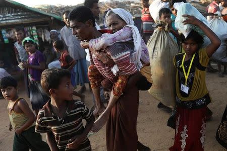 Rohingya refugee Suray Khatun, 70, is carried by her son Said-A-Lam, 38, as they enter Kutupalong refugee camp, near Cox's Bazar, Bangladesh a day after crossing the Myanmar border, November 20, 2017. REUTERS/Susana Vera